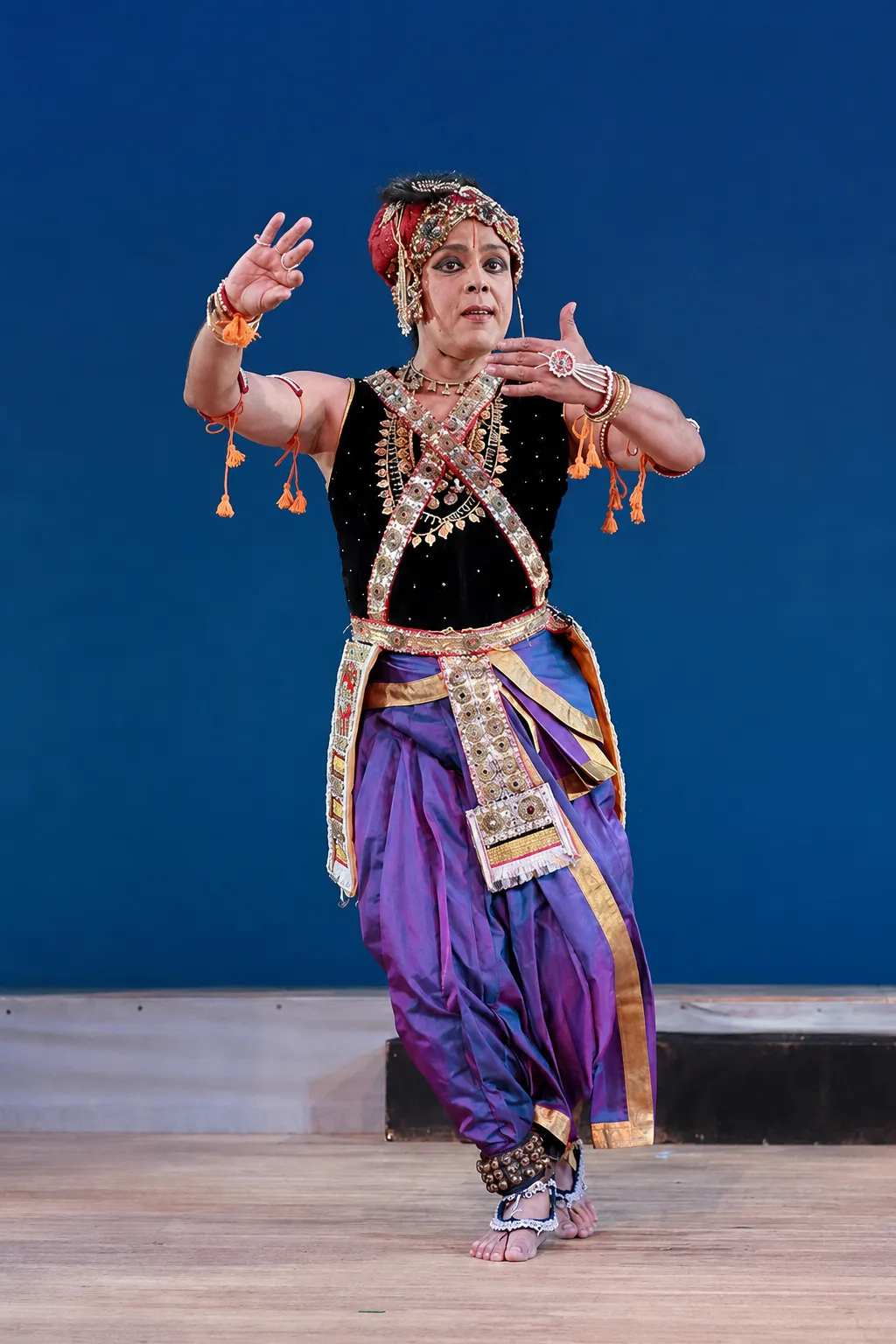 Sanjib performing Manipuri dance in purple costume on a blue-lit stage