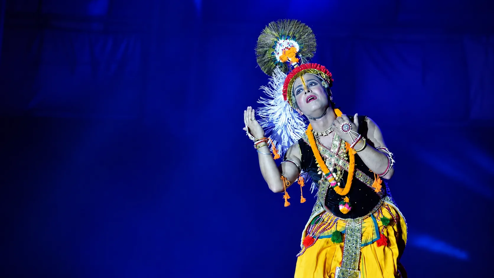 Sanjib as Krishna in a graceful pose on a deep-blue stage